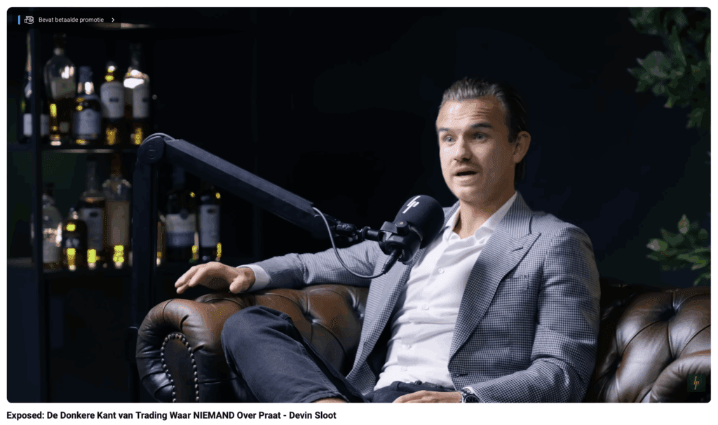 Een man in een grijs pak zit in een podcaststudio en praat in een microfoon over de misleidende kant van trading.